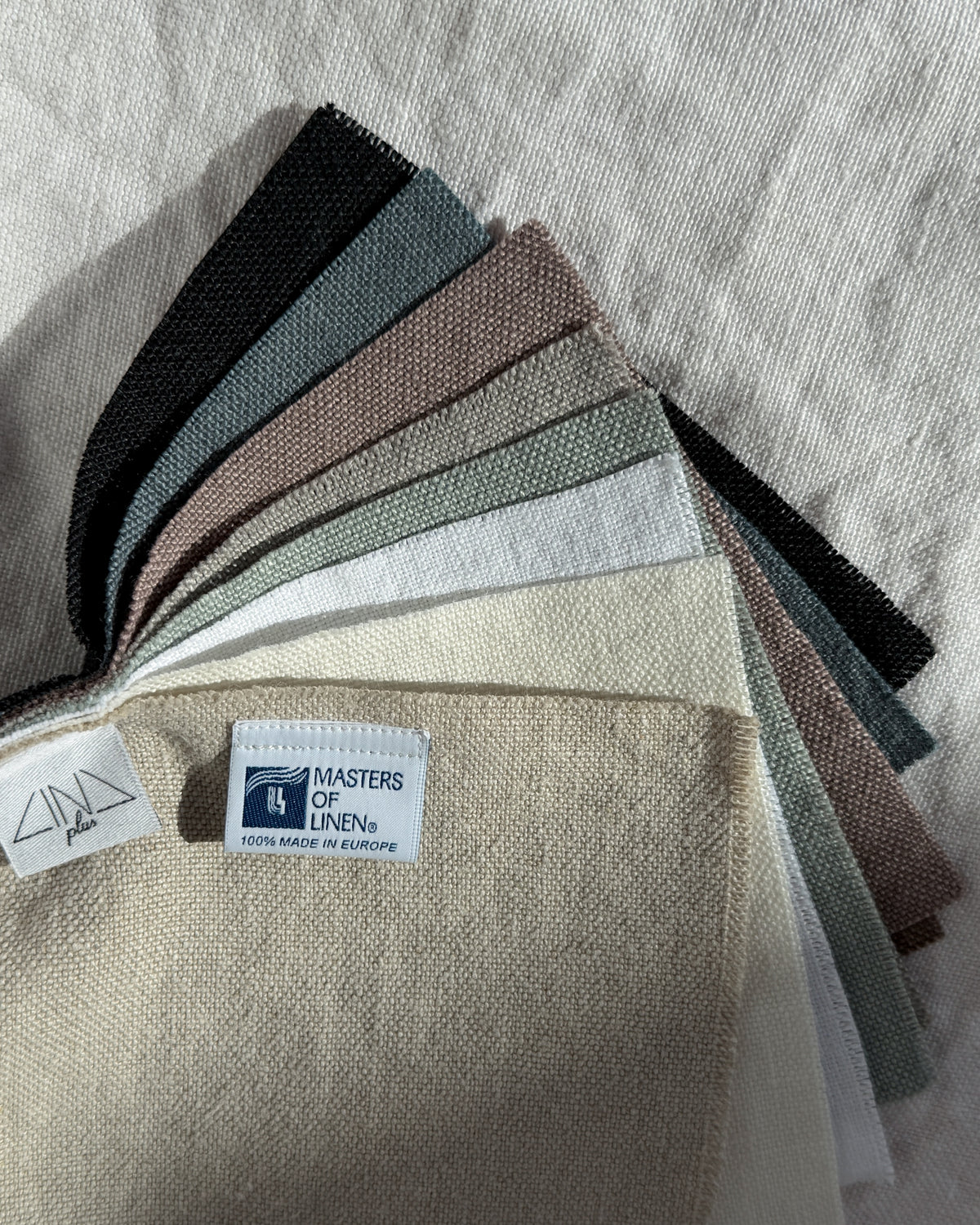 Fanned linen fabric sample swatches in neutral tones from black to cream