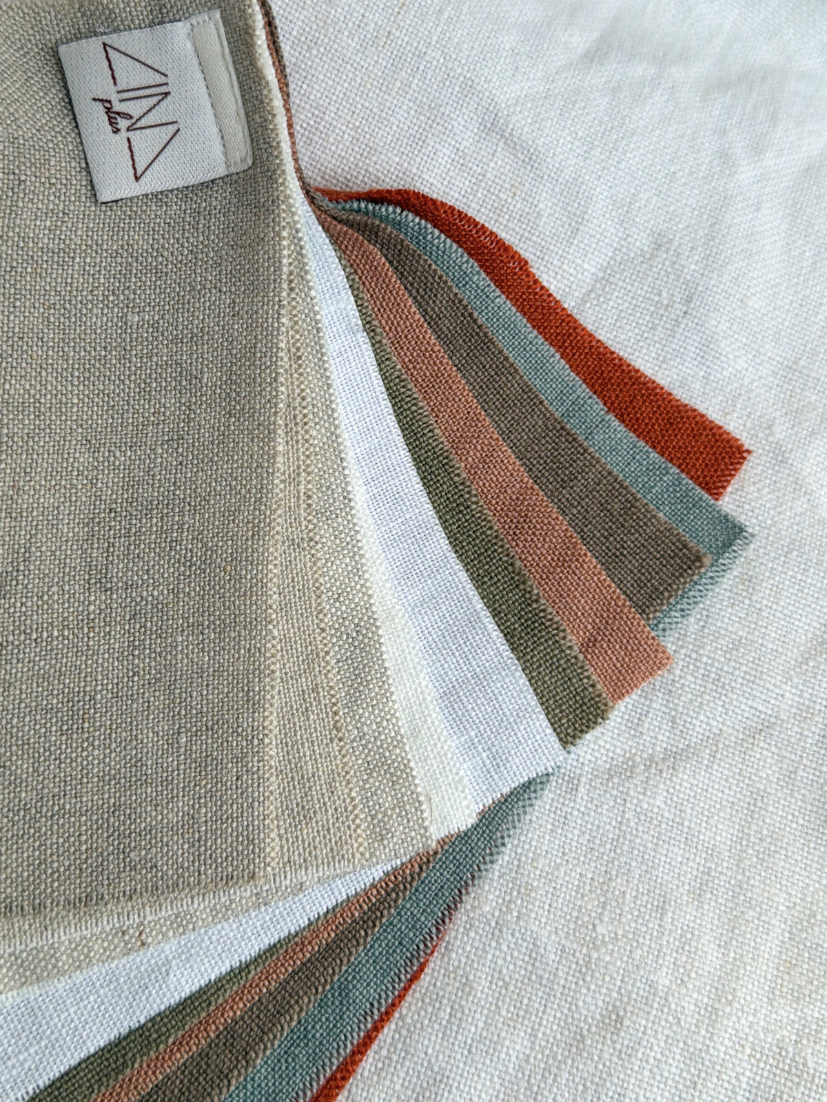 Linen Samples LINONATA fabric swatches in neutral and colored tones fanned out, displaying texture and weave