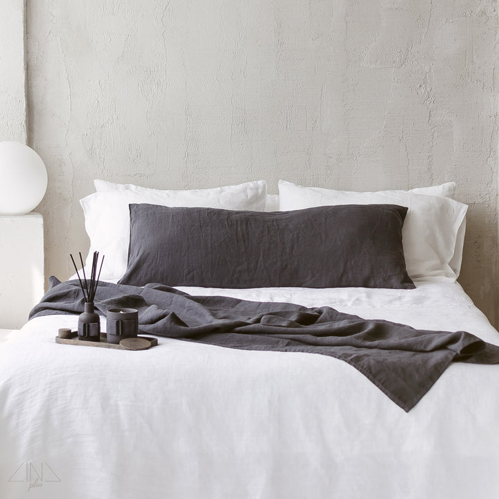 Linen pillowcase displayed on bed with white sheets and dark linen throw